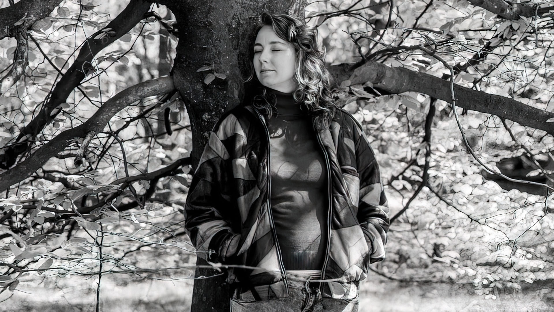 Een zwart-witfoto van Anouk Brinkman leunend tegen een boom.
