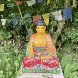 In een serene tuin straalt een statige boeddha rust uit en belichaamt het Magic Mantra Weekend Fryslân.