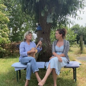 Twee vrouwen zittend op een bankje onder een boom in Fryslân, genietend van een Magic Mantra Weekend Friesland | Magisch weekend vol mantra's.