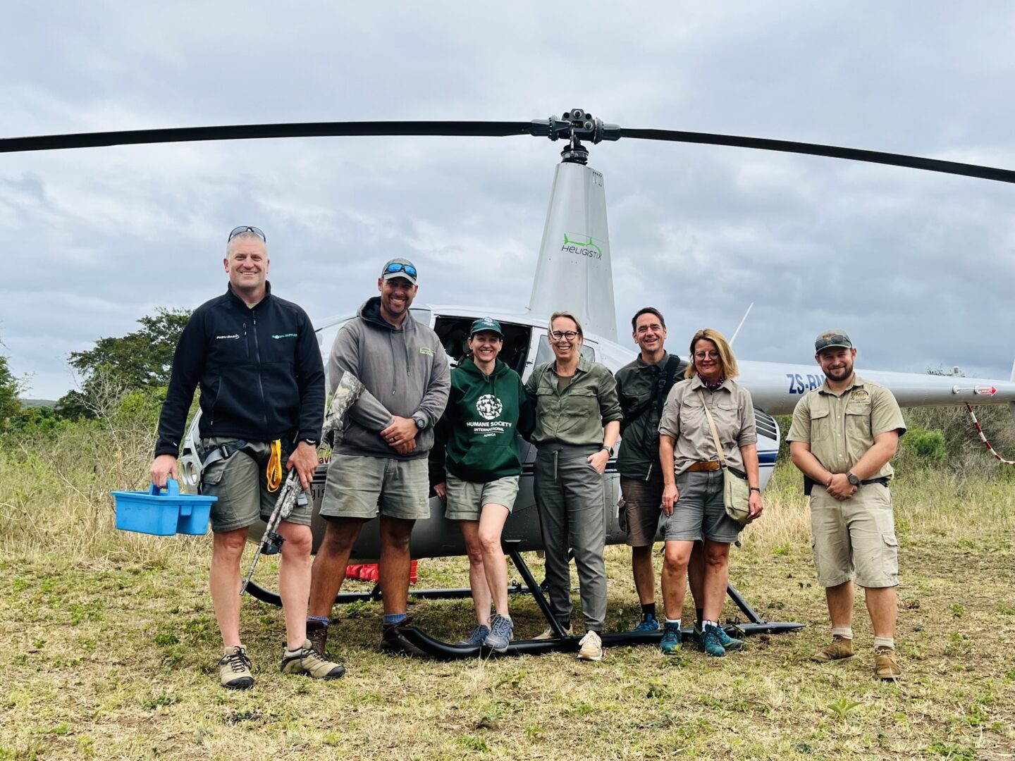 Een groep mensen staat voor een helikopter.