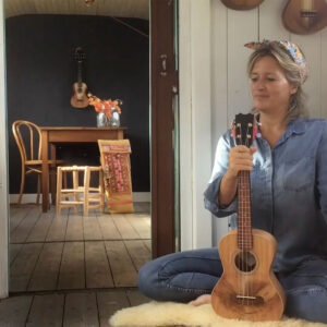 Een vrouw die ukelele speelt in het gezellige huis met open haard.